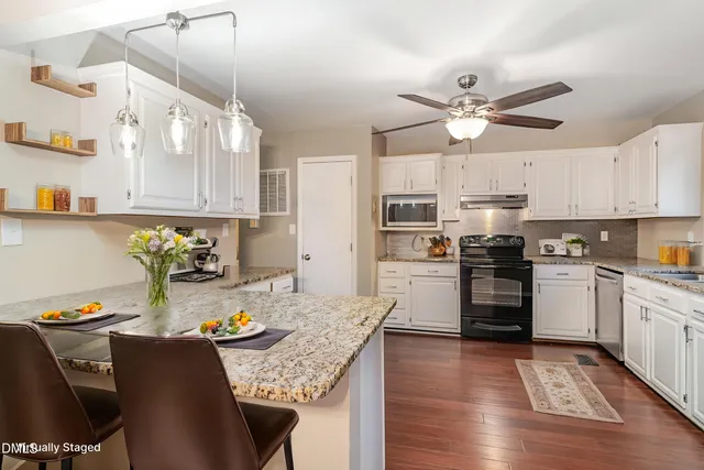 a kitchen with granite countertop kitchen island stainless steel appliances a stove a sink a refrigerator cabinets and dining table