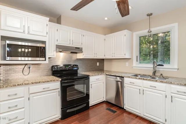 a kitchen with granite countertop white cabinets white stainless steel appliances and sink
