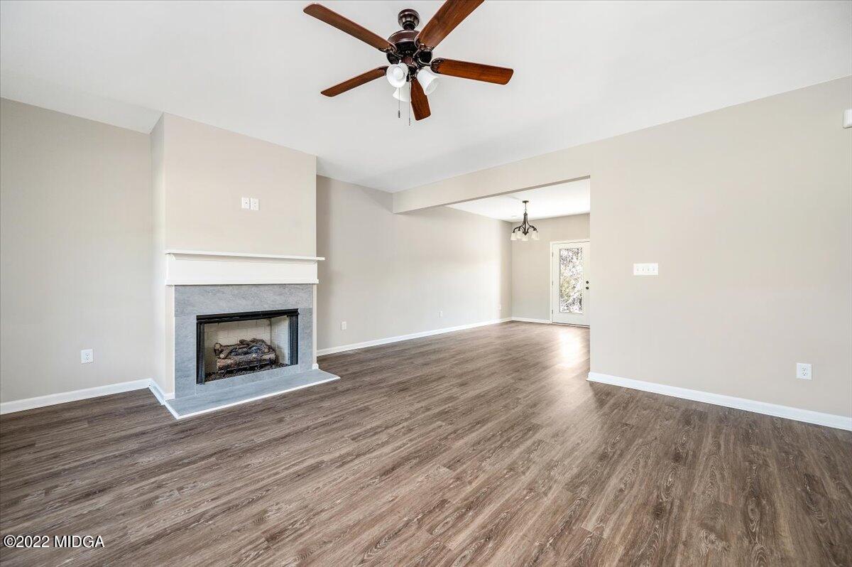 229 Davis Road Gray, GA 31032 - Photo 4 of 30 an empty room with wooden floor a fireplace and a ceiling fan