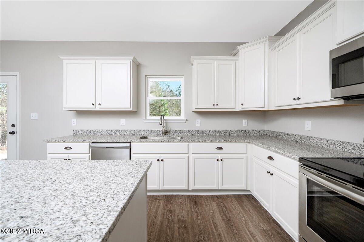 229 Davis Road Gray, GA 31032 - Photo 10 of 30 a kitchen with stainless steel appliances granite countertop a stove a sink and white cabinets