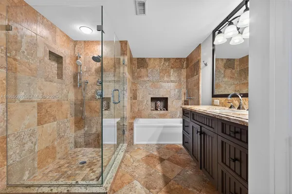 a bathroom with a tub sink shower and mirror