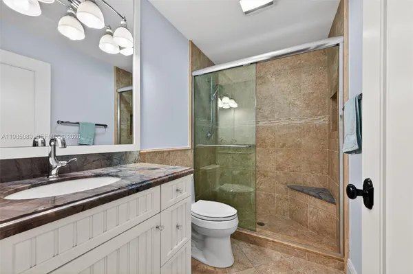 a bathroom with a granite countertop sink toilet a mirror and shower