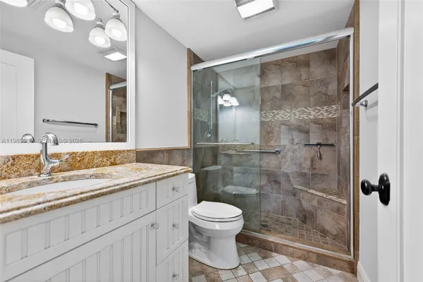 a bathroom with a granite countertop sink toilet a mirror and shower