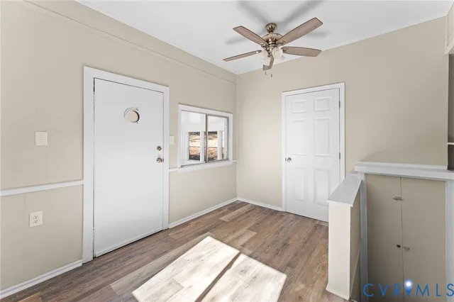 an empty room with wooden floor and ceiling fan