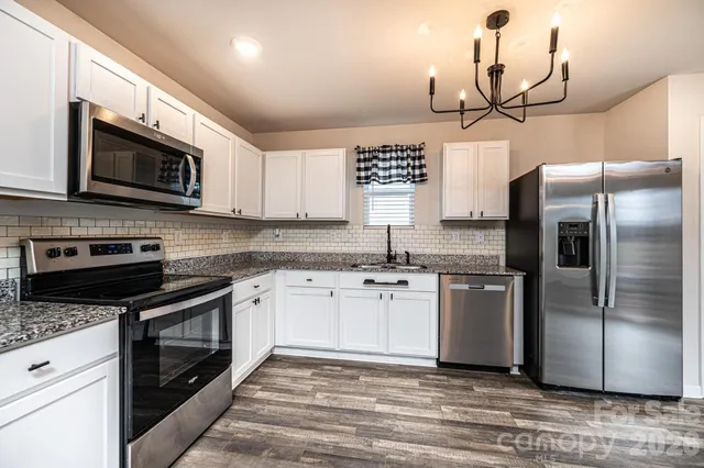 a kitchen with stainless steel appliances granite countertop a refrigerator a stove a sink and a microwave