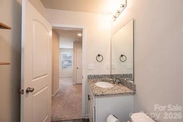 a bathroom with a granite countertop sink mirror vanity and toilet