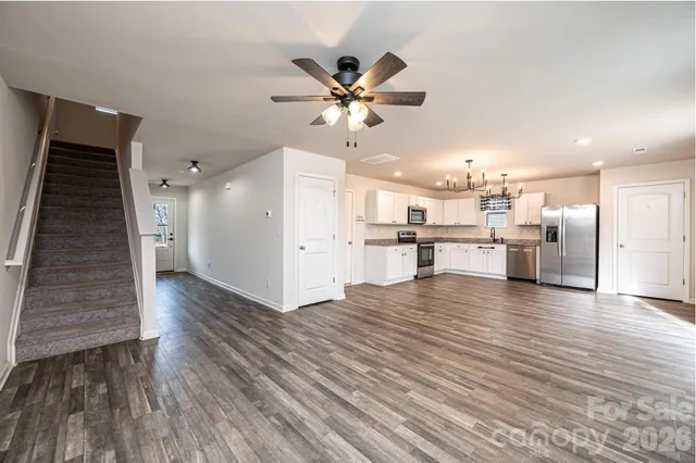 a view of a kitchen with a refrigerator a ceiling fan and wooden floor