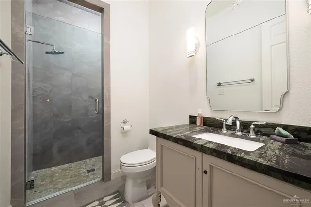 a bathroom with a granite countertop sink a toilet and shower