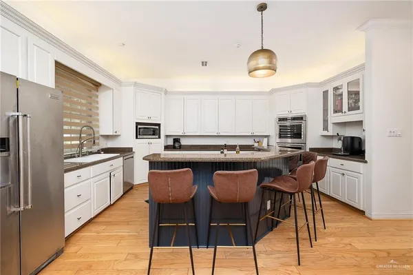 a kitchen with stainless steel appliances granite countertop a stove a sink dishwasher a refrigerator with a dining table and chairs