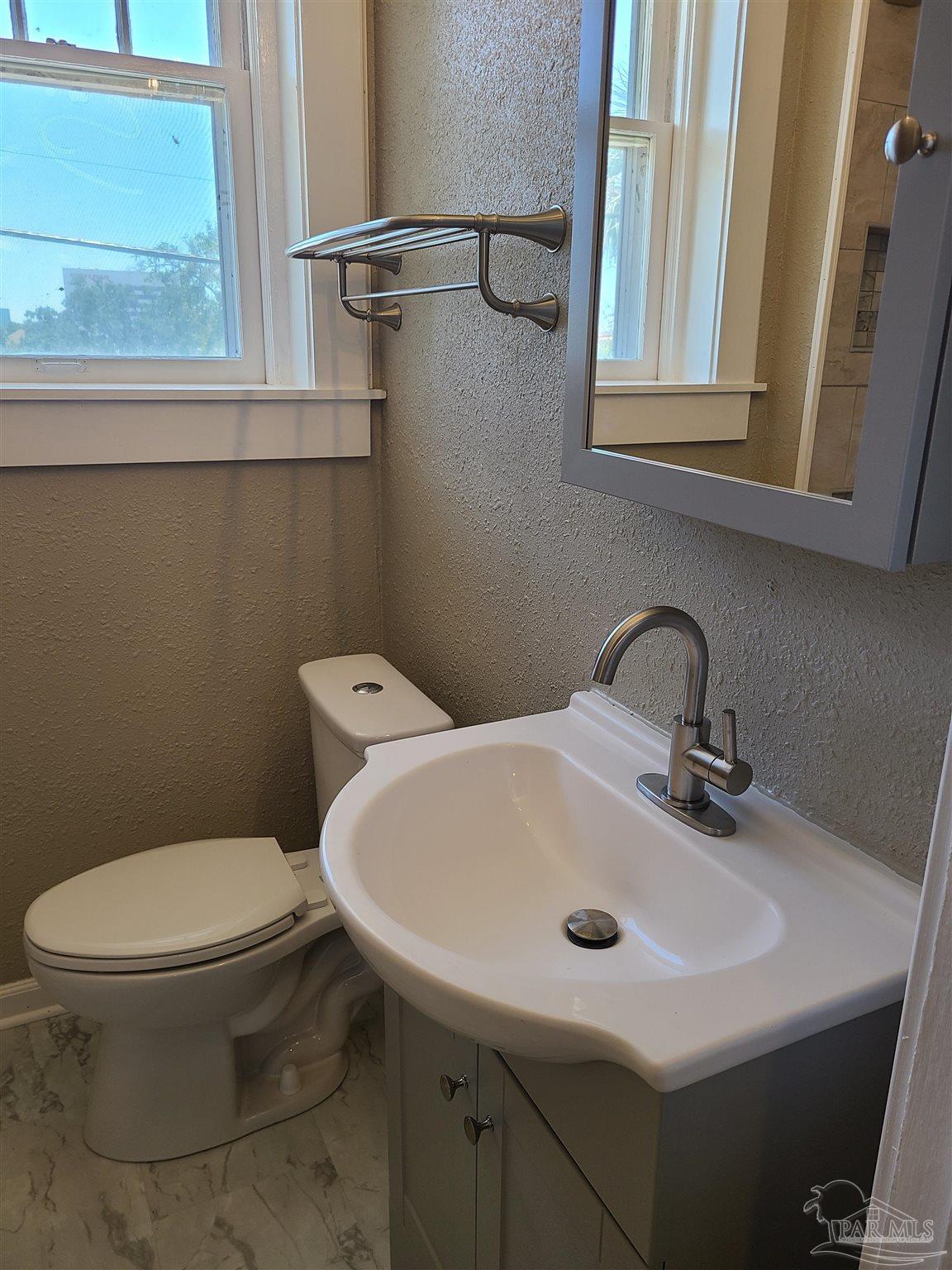 504 North Spring Street, Unit B Pensacola, FL 32501 - Photo 11 of 14 a bathroom with a sink a toilet and a window