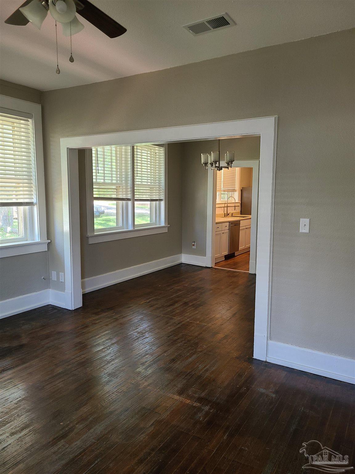 504 North Spring Street, Unit B Pensacola, FL 32501 - Photo 2 of 14 an empty room with wooden floor and windows