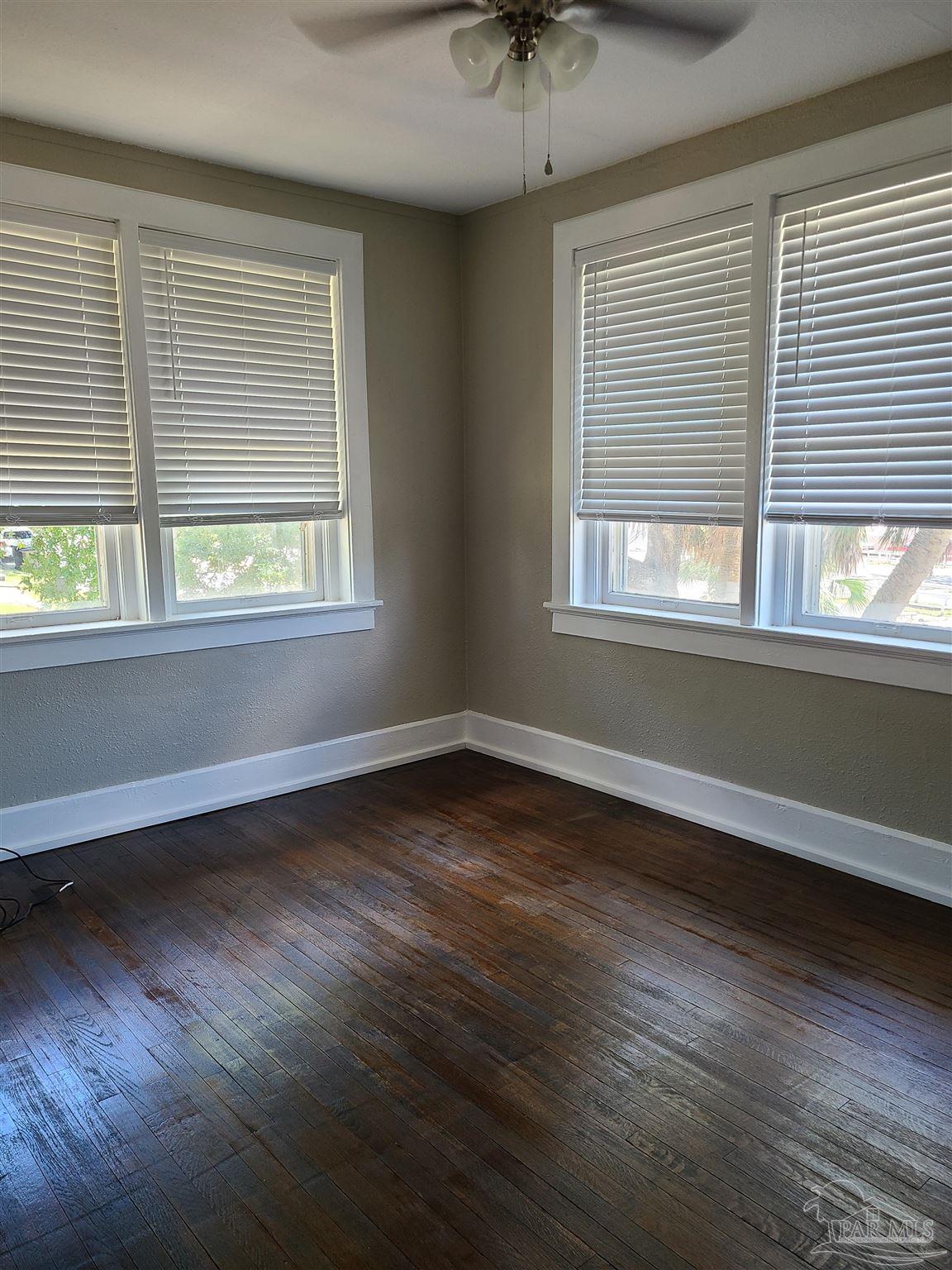 504 North Spring Street, Unit B Pensacola, FL 32501 - Photo 8 of 14 an empty room with wooden floor and windows