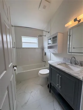 a bathroom with a granite countertop toilet a sink and a mirror