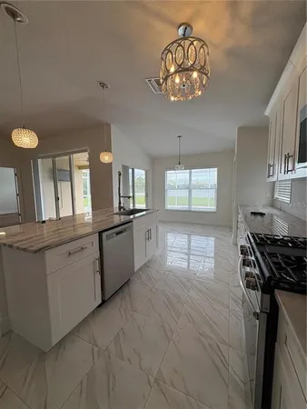 a kitchen with granite countertop a stove a sink dishwasher and white cabinets with wooden floor