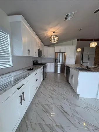 a kitchen with granite countertop a sink cabinets and stainless steel appliances