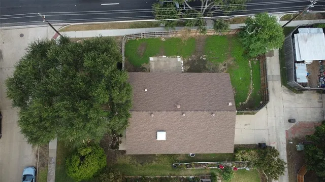 an aerial view of a house with a yard and a large tree