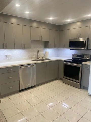a kitchen with stainless steel appliances granite countertop a sink and a stove top oven with white cabinets