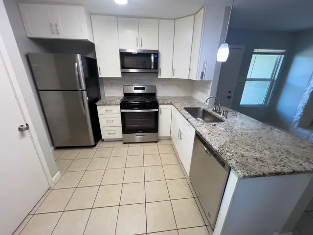 a kitchen with granite countertop a refrigerator sink and microwave