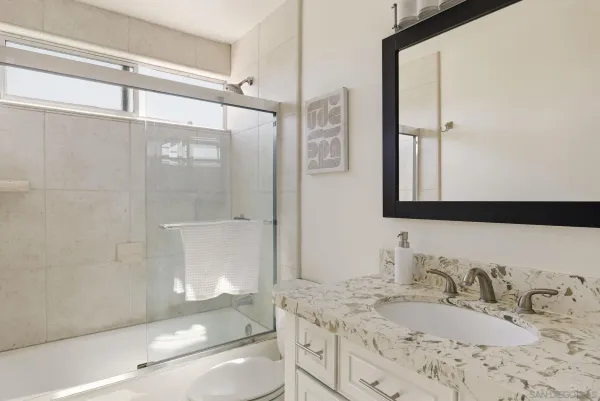 a bathroom with a granite countertop sink toilet and shower