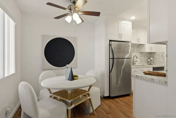 a kitchen with stainless steel appliances granite countertop a refrigerator a stove and a dining table with wooden floor