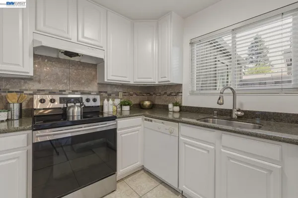 a kitchen with granite countertop white cabinets and white stainless steel appliances