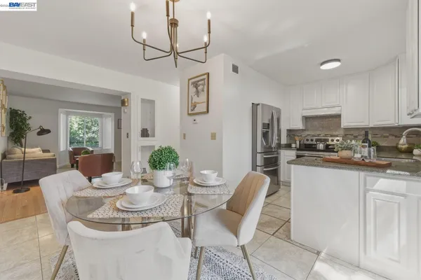 a kitchen with stainless steel appliances kitchen island granite countertop a dining table chairs and a refrigerator