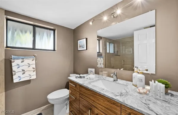 a bathroom with a granite countertop sink mirror and toilet