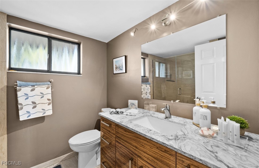 413 Augusta Boulevard, Unit 302 Naples, FL 34113 - Photo 13 of 22 a bathroom with a granite countertop sink mirror and toilet