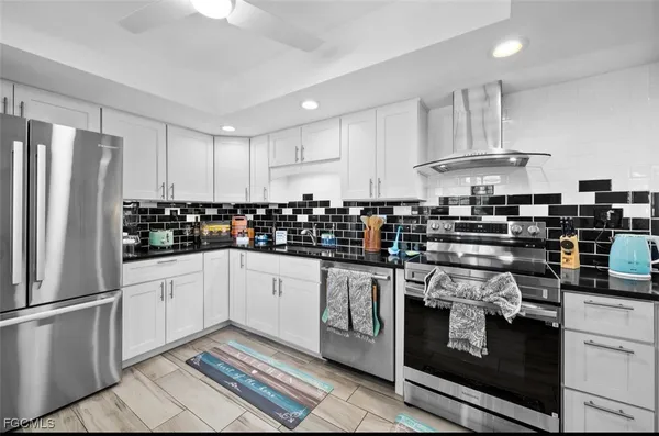 a kitchen with granite countertop a refrigerator stove top oven and sink