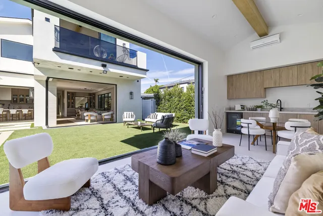 a living room with patio furniture and a garden