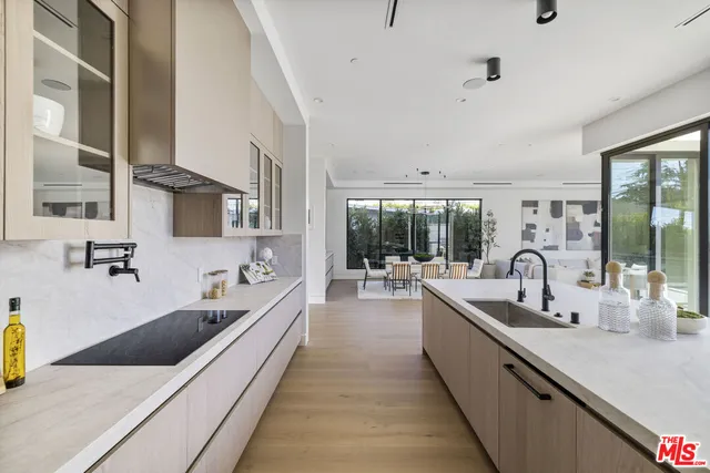 a large white kitchen with stainless steel appliances a sink and cabinets