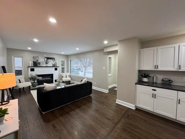 a living room with furniture a fireplace a flat screen tv and kitchen view