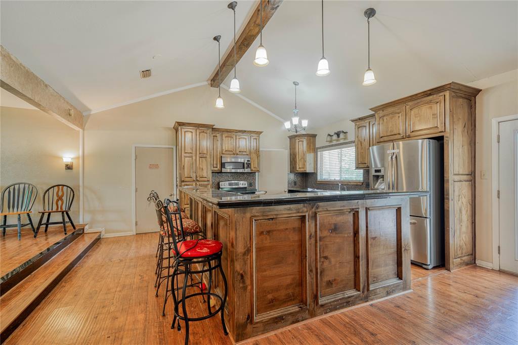 1006 Rikkity Lane Mount Pleasant, TX 75455 - Photo 5 of 39 a kitchen with stainless steel appliances granite countertop a refrigerator a sink dishwasher a dining table and chairs with wooden floor
