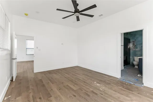 a view of a big room with wooden floor a ceiling fan and windows