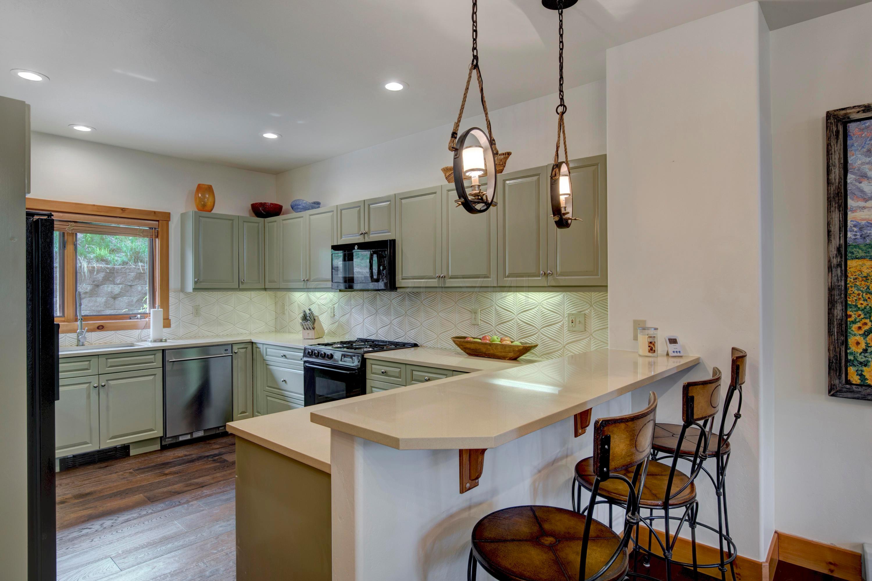 92 Knudson Ranch Road Edwards, CO 81632 - Photo 8 of 26 a kitchen with stainless steel appliances granite countertop a sink a stove a kitchen island with chairs and wooden floor