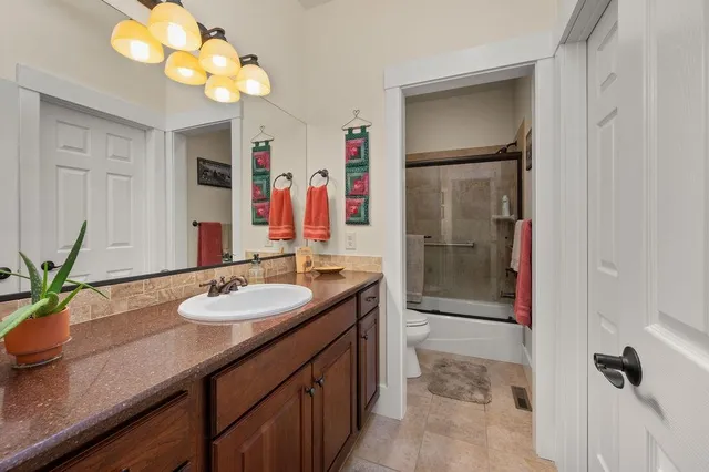 a bathroom with a granite countertop sink a mirror and a shower