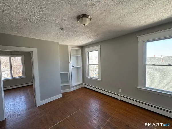 an empty room with wooden floor and windows