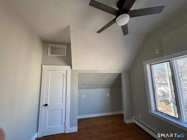 an empty room with wooden floor closet and windows