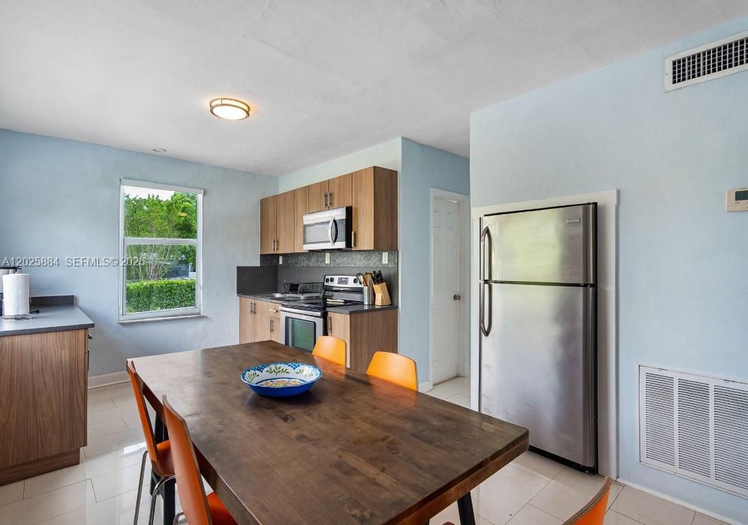 2255 Southwest 10th Street, Unit B Miami, FL 33135 - Photo 13 of 26 a kitchen with stainless steel appliances granite countertop a refrigerator a stove a sink a dining table and chairs with wooden floor