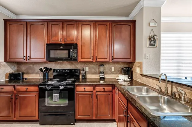 a kitchen with granite countertop stainless steel appliances stove microwave refrigerator and cabinets