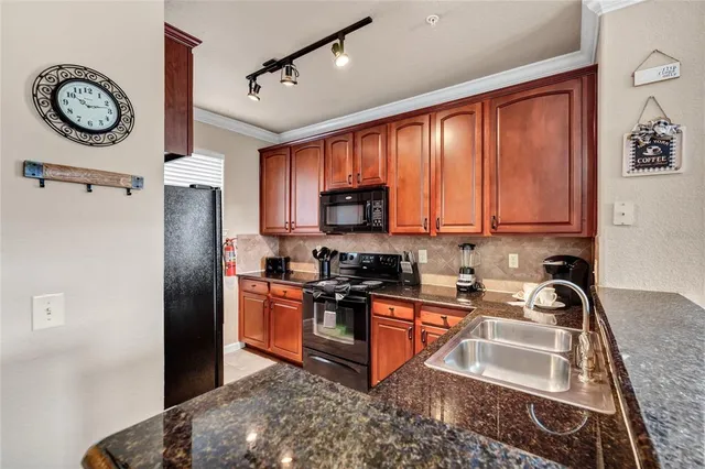 a kitchen with stainless steel appliances granite countertop a refrigerator a stove and a sink with granite countertops