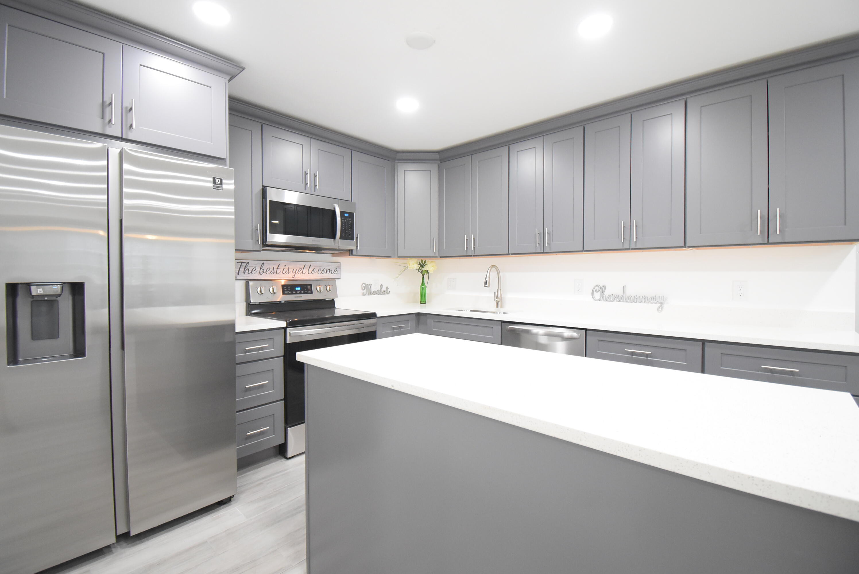 5047 Heatherhill Lane, Unit 60 Boca Raton, FL 33486 - Photo 1 of 34 a kitchen with a refrigerator a microwave oven and a sink with wooden cabinets