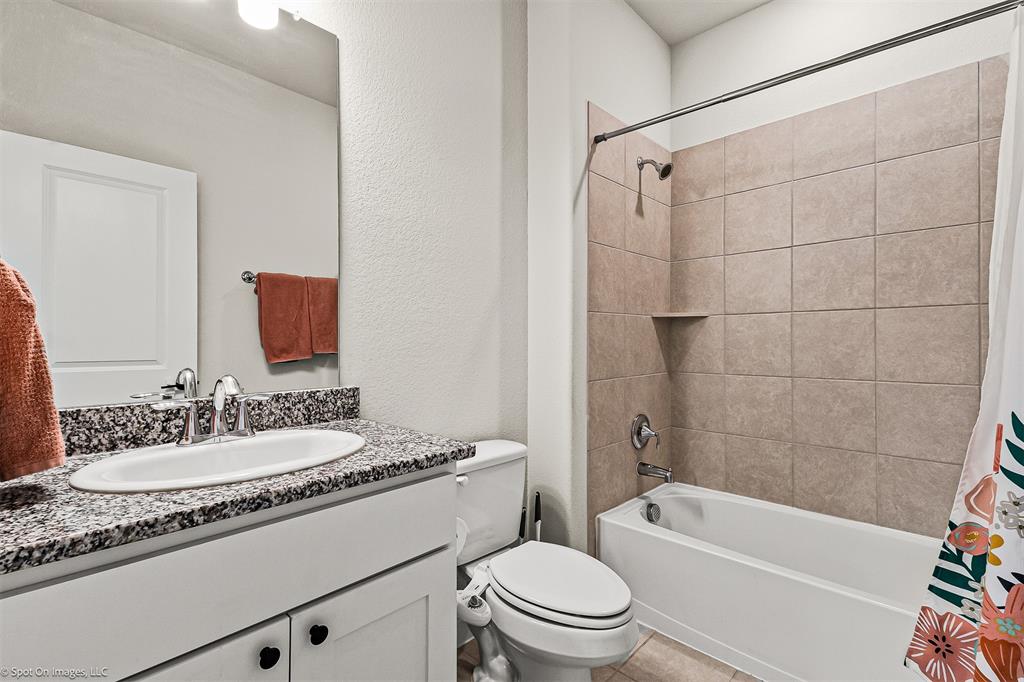 904 Vineyard Way Forney, TX 75126 - Photo 34 of 38 a bathroom with a granite countertop sink a toilet a mirror a bathtub and shower