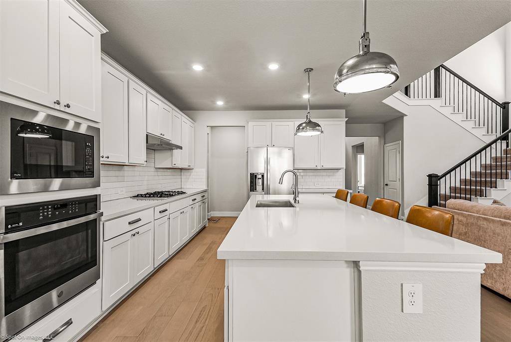 904 Vineyard Way Forney, TX 75126 - Photo 10 of 38 a kitchen with stainless steel appliances a stove a microwave and white cabinets