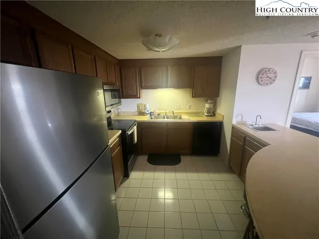 a kitchen with stainless steel appliances a sink a stove a refrigerator and cabinets