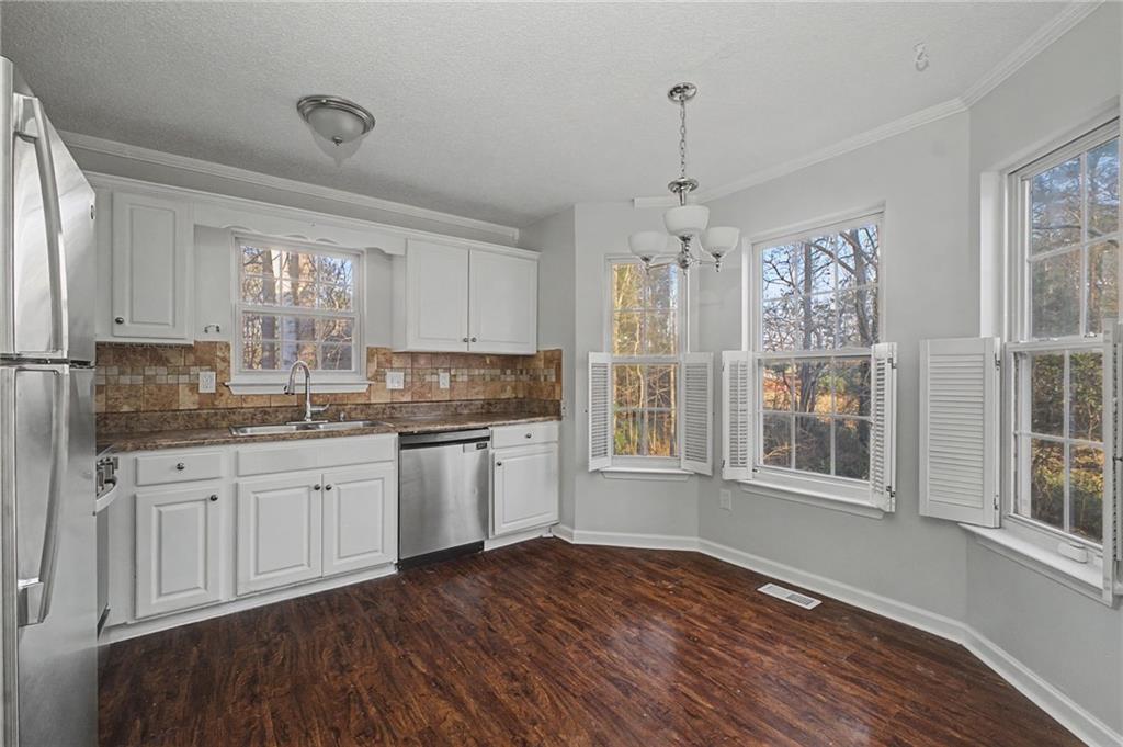 4244 Akins Ridge Lane Powder Springs, GA 30127 - Photo 15 of 37 a kitchen with granite countertop a stove a sink and white cabinets with wooden floor