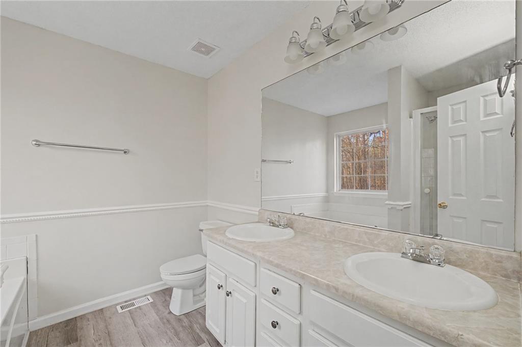 4244 Akins Ridge Lane Powder Springs, GA 30127 - Photo 24 of 37 a bathroom with a granite countertop sink a toilet and a large mirror