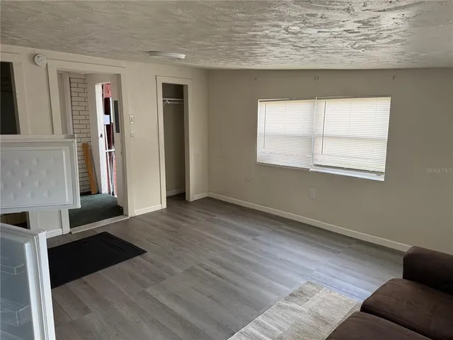 an empty room with wooden floor cabinet and windows