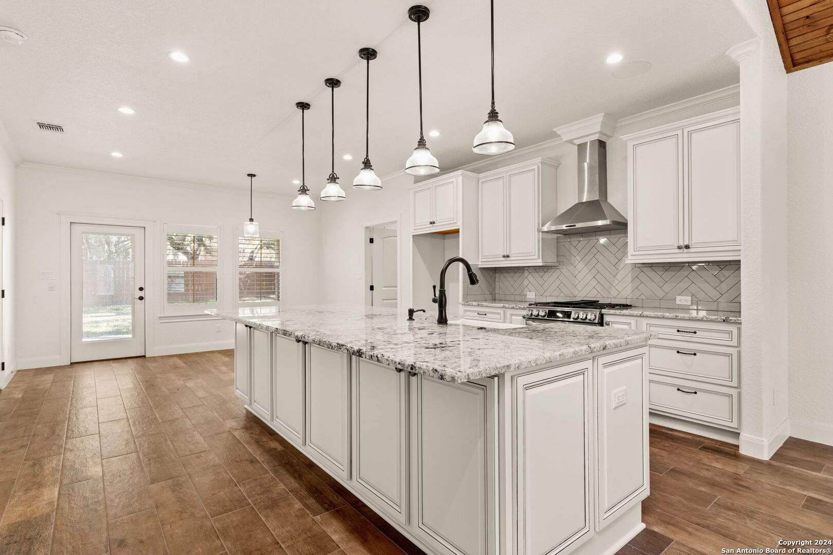 a large kitchen with kitchen island a stove a sink a center island and wooden floor