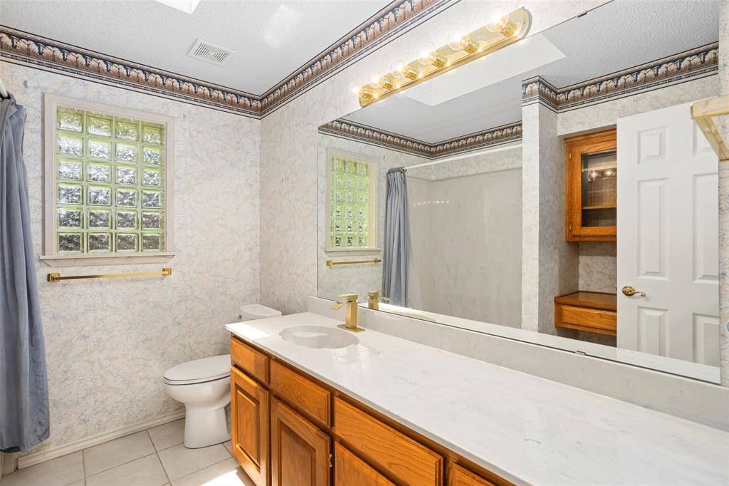 5522 Wedgefield Road Granbury, TX 76049 - Photo 18 of 22 a bathroom with a granite countertop sink toilet and a mirror